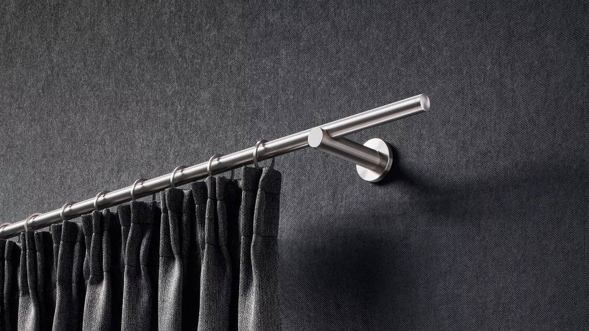 Edelstahl Gardinenstange mit Ringen und einem dunklen Vorhang an der Wand vor einem Fenster montiert