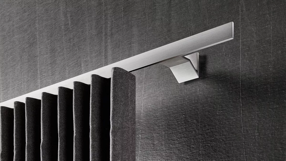 Interstil Gardinenstange in der Farbe Edelstahl an der Wand montiert mit einem dunklen Vorhang