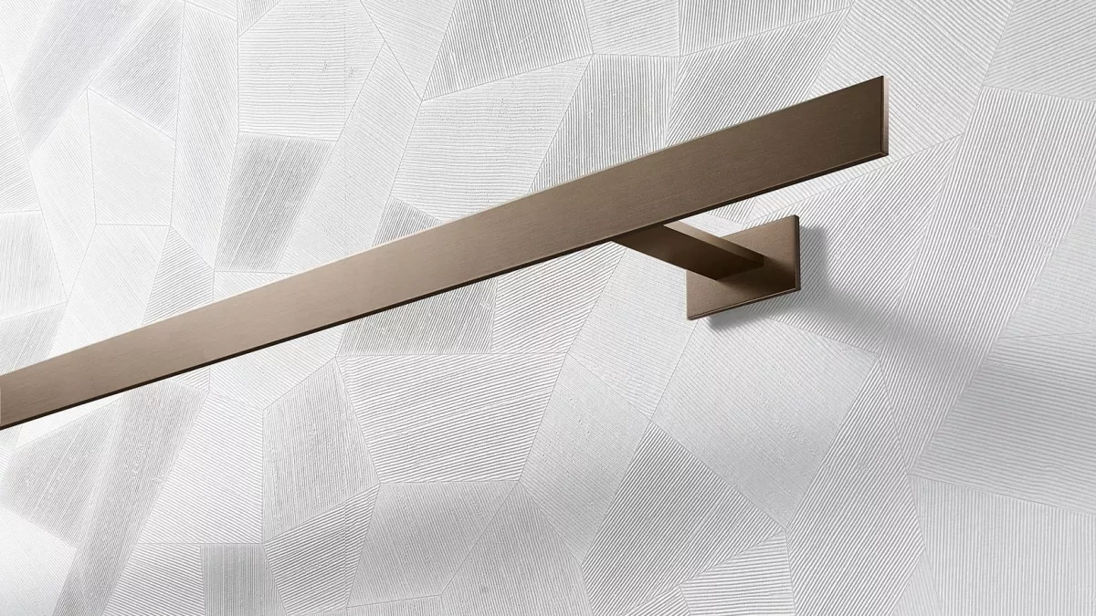 Interstil Gardinenstange Codex in der Farbe Bronze an einer gemusterten Wand vor einem Fenster montiert