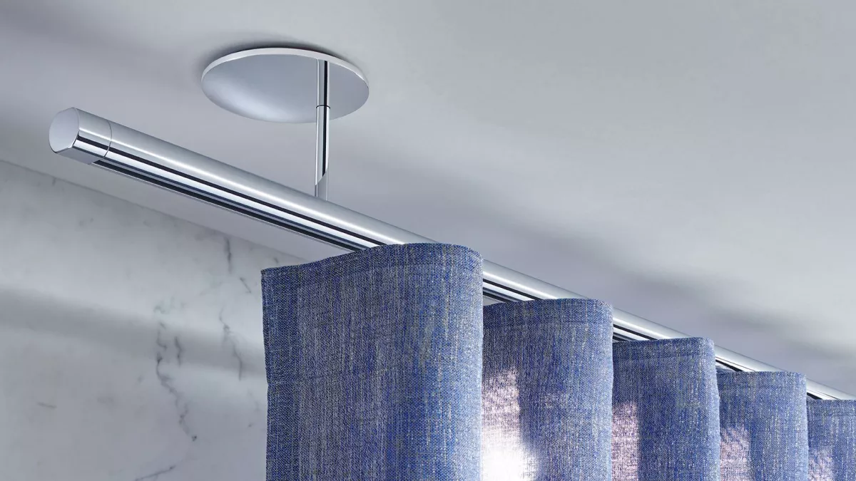 Interstil Gardinenstange Zenit-W in der Farbe Chrom an der Decke vor einem Fenster montiert mit einem leichten Wellenvorhang