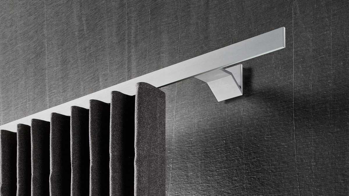 Interstil Gardinenstange in der Farbe Aluminium an der Wand montiert mit einem dunklen Vorhang